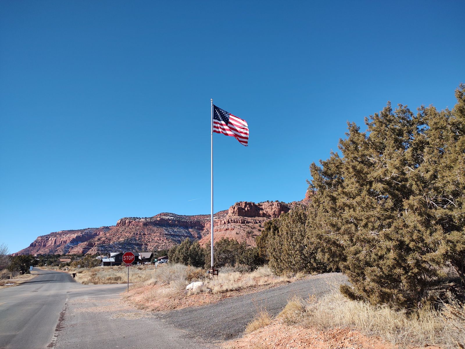 American flag flying against red desert cliffs and a blue sky